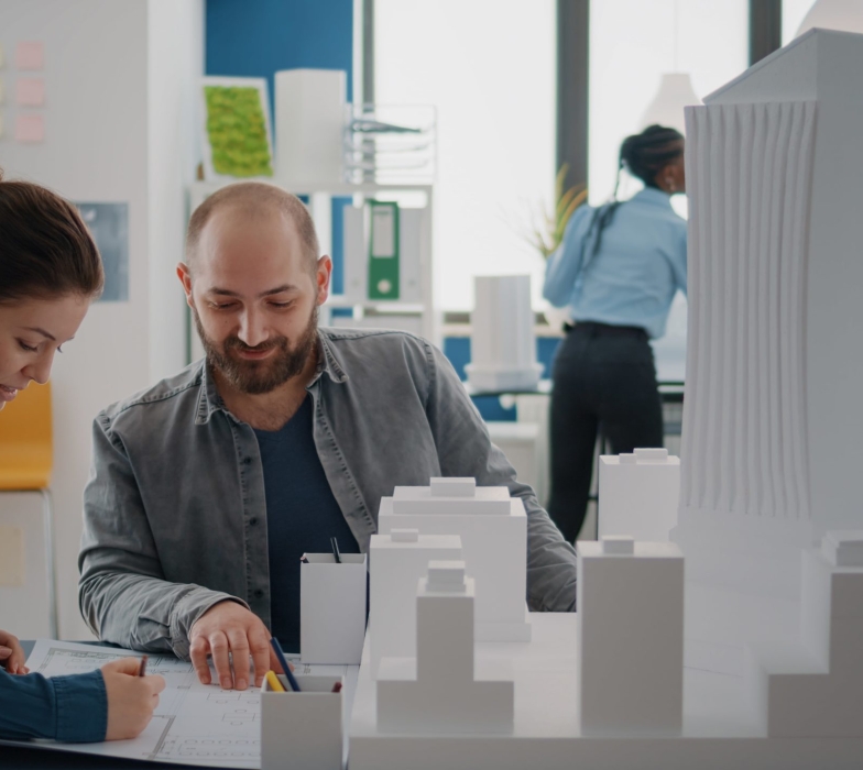 team-coworkers-analyzing-building-model-blueprints-plan-table-design-construction-layout-architectural-colleagues-doing-teamwork-designing-project-development-together-min